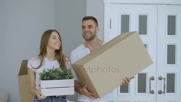Happy couple watching their new home excited. Young woman give keys to her boyfriend and kissing him - Filmati, video