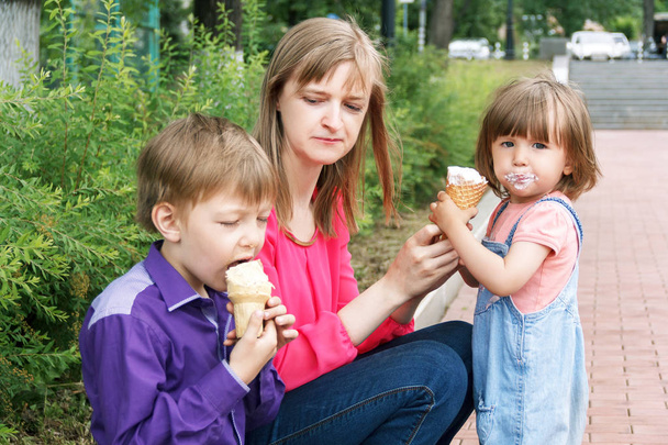 Rodzina siedzący w lato park jedzenie lodów - Zdjęcie, obraz