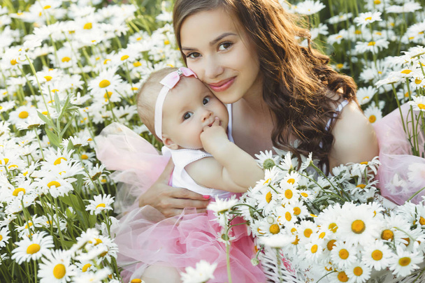 Jonge mooie moeder met haar kleine baby outdoors. Mooie wom - Foto, afbeelding