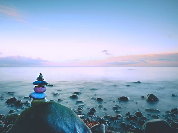 Στρογγυλεμένες πολύχρωμες πέτρες στέκονται με τη μορφή πυραμίδας μεγάλη στρογγυλεμένη πέτρα στη θάλασσα - Φωτογραφία, εικόνα