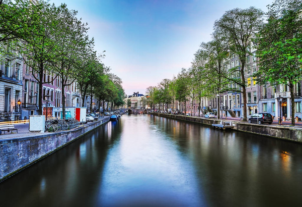 Самые известные каналы и набережные Амстердама во время заката. Общий вид городского ландшафта и традиционной архитектуры Нидерландов
. - Фото, изображение