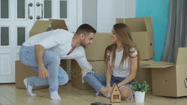 Šťastný pár sedí na podlaze v novém domě. Mladý muž dát klíče k jeho přítelkyni a políbil ji - Záběry, video