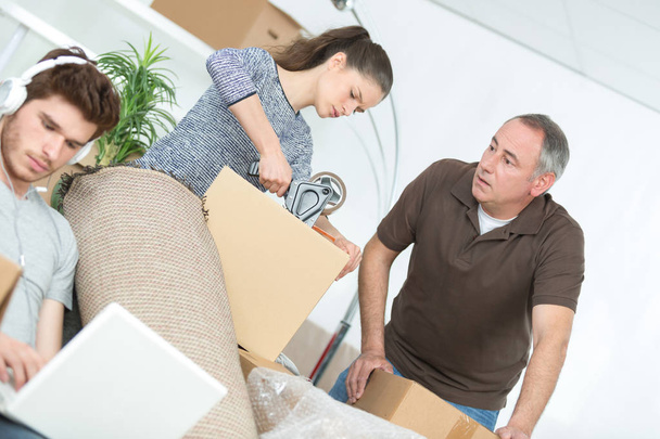 woman and father packing boxes and his lazy boyfriend - Foto, imagen