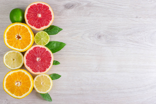 Šťavnaté citrusové plody řez list máty pozadí. Pomeranče, citrony, limetky, grapefruity, máta listy na světlé dřevěné pozadí - Fotografie, Obrázek