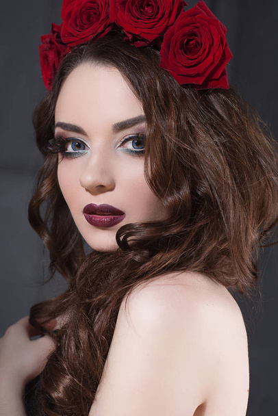 piękna młoda kobieta z róż kwiat we włosach. piękna dziewczyna z makijażu na ciemnym tle. ciemny czerwony lips.close-up moda retuszowane portret - Zdjęcie, obraz