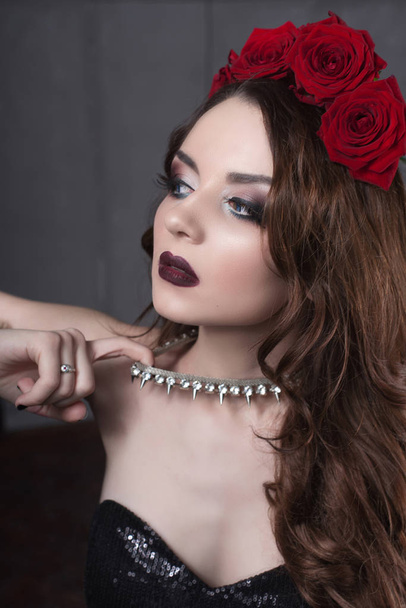 hermosa joven con flores de rosas en el pelo. chica de belleza con maquillaje sobre fondo oscuro. rojo oscuro lips.close-up retrato retocado de moda
 - Foto, imagen