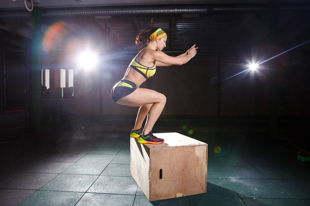 Young, strong muscular girl jumps in the gym to the elevation. Leg training and cardio - Foto, imagen
