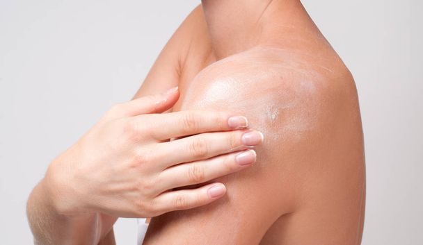 Body care. Woman cares about her shoulder applying cosmetic cream - Фото, зображення