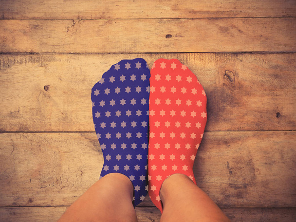 feet wearing blue and red socks with white star shape on wooden  - Photo, Image
