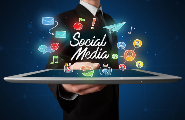 Businessman holding tablet with social media graphics - Foto, Imagem