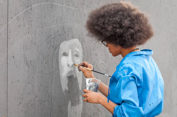 Ukraine, Nikolaev, 24.06.17: Festival of graffiti dedicated to the Day of Youth. The central square of the city. Young beautiful African-American girl Sandra Sambo draws graffiti. - 写真・画像