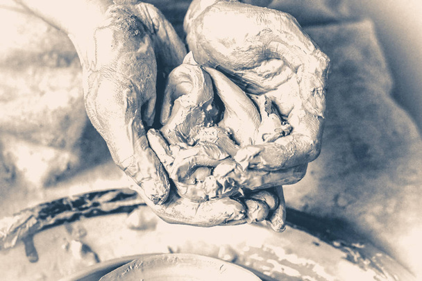 Kneed, raminanie klei in de handen van de mens. Oude vintage stijl. - Foto, afbeelding