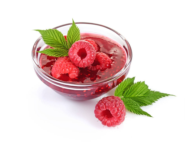 Close up view jam in glass bowl with fresh ripe raspberry and leaves - Photo, Image