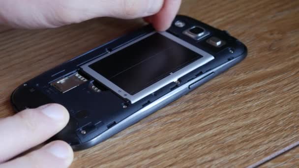 De hand neemt de batterij uit de smartphone - Video