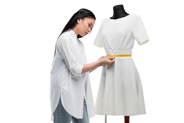 азиатский портниха измеряет платье на манекен
 - Фото, изображение