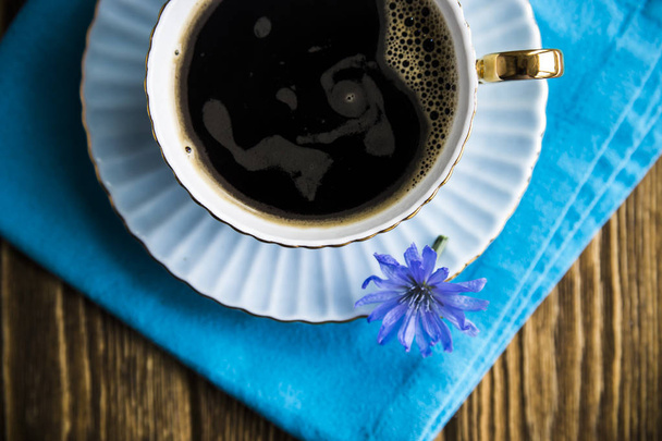 Blue chicory flowers next to a cup of hot drink - Foto, imagen