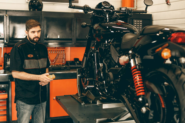 Professional moto mechanic raises a motorcycle on the lift. - Zdjęcie, obraz