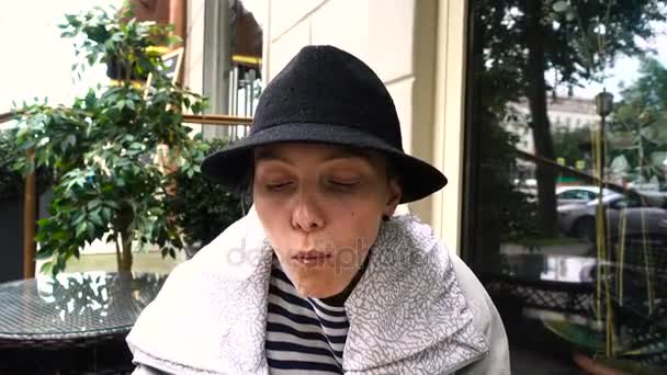 Γυναίκα με καπέλο τρώει χάμπουργκερ στο δρόμο - Πλάνα, βίντεο