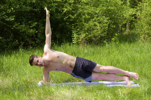 Sportive man with six packs does exercises on yoga mat - Zdjęcie, obraz