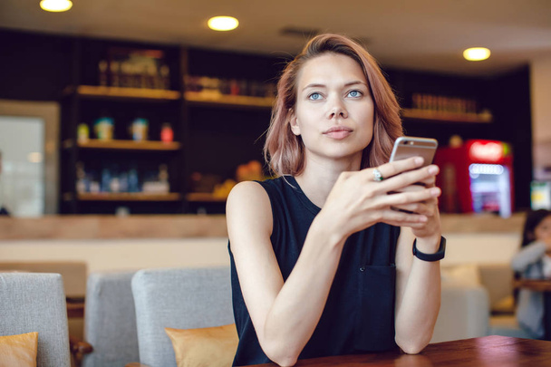 Attractive woman using smartphone in a cafe. - Foto, Imagen