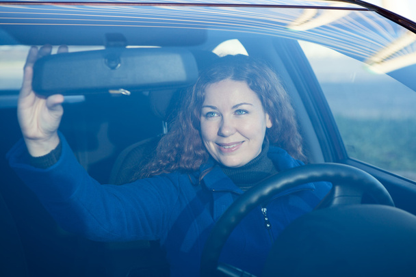 Pretty woman in car preparing to driving correcting back mirror - Photo, image