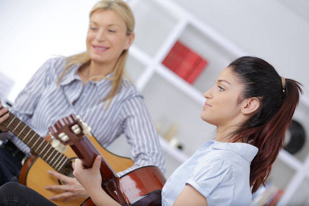 mother and daughter playing guitar together - Fotografie, Obrázek
