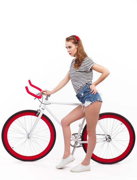 Serious young woman with bicycle on white - Φωτογραφία, εικόνα