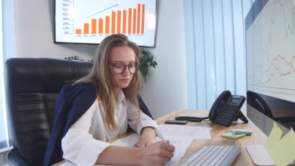 Όμορφη νεαρή γυναίκα που εργάζεται με έγγραφα στο γραφείο - Πλάνα, βίντεο