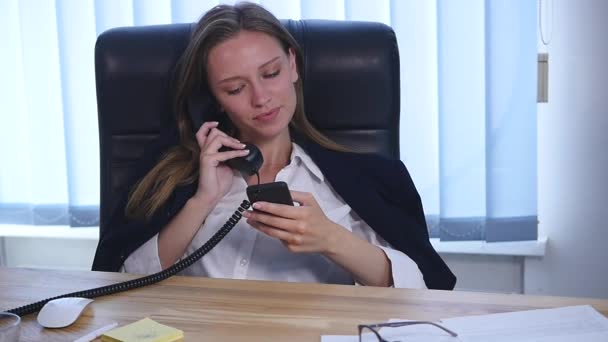 Joven atractiva empresaria hablando por teléfono y usando smartphone en la oficina y sonriendo
 - Imágenes, Vídeo