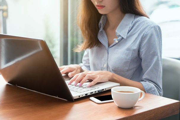 Γυναίκα χρησιμοποιώντας ένα φορητό υπολογιστή κατά τη διάρκεια της διάλειμμα για καφέ, τα κοντά χέρια επάνω - Φωτογραφία, εικόνα