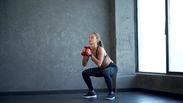 Genç fitness kadın elinde dumbbells ile ağız kavgası yapıyor. Spor salonunda sahne - Video, Çekim