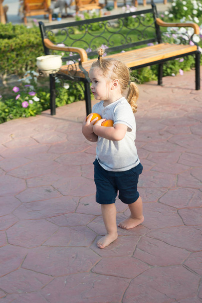 Cute baby boy walking barefoot with two oranges - Φωτογραφία, εικόνα