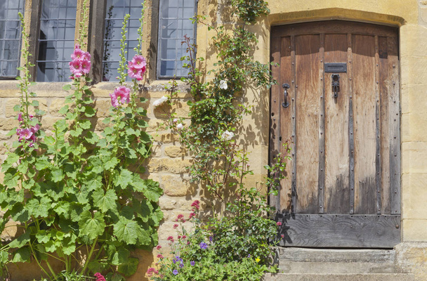 Huis deuren in een Engelse cottage met kleurrijke bloemen op de voorgrond - Foto, afbeelding