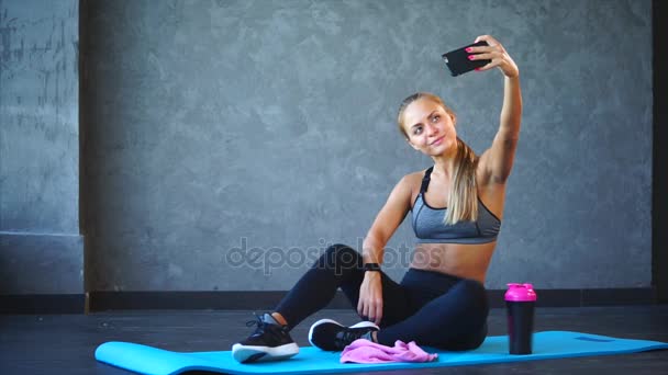Uma mulher de esportes tira fotos no telefone depois de um treino em um clube de fitness
 - Filmagem, Vídeo
