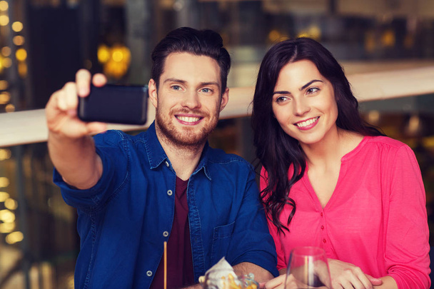 couple taking selfie by smartphone at restaurant - Фото, зображення
