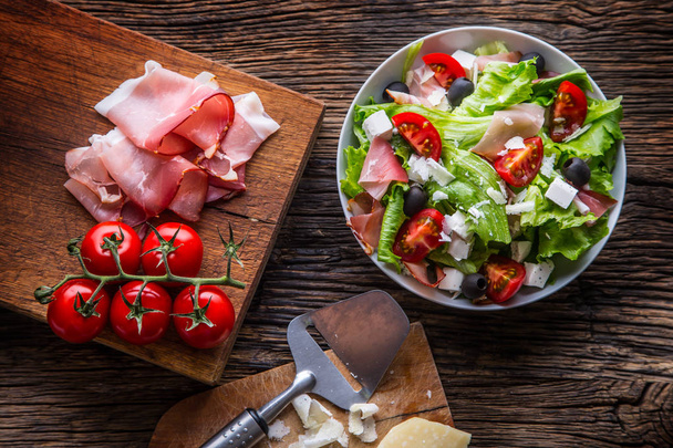 Salad. Fresh summer lettuce salad.Healthy mediterranean salad olives tomatoes parmesan cheese and prosciutto - Фото, изображение