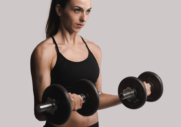  woman in a workout gear lifting dumbbells - Foto, afbeelding