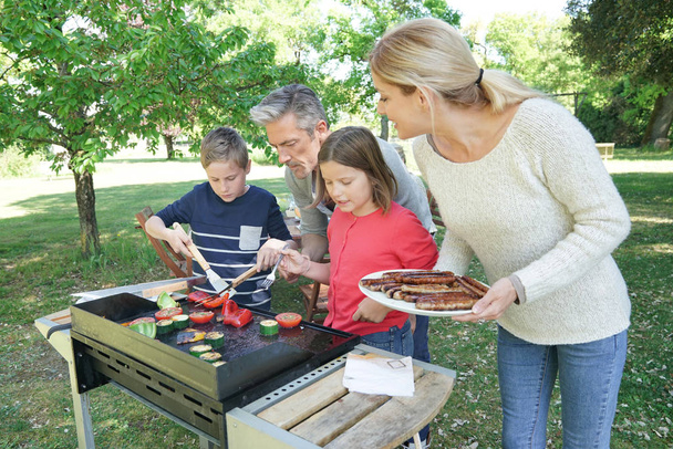 Family preparing grilled meet - 写真・画像