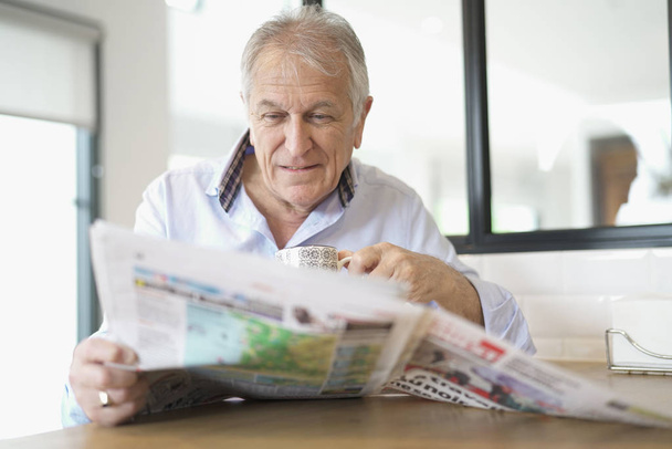 man at home reading newspaper - Foto, afbeelding