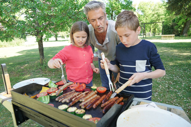 Father with kids preparing barbecue - Foto, imagen