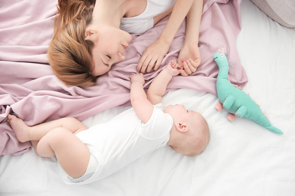 Young woman with cute baby sleeping on bed at home - Foto, Bild