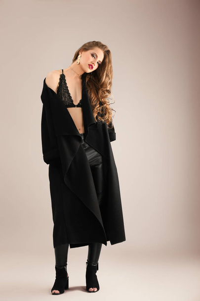 Beautiful stylish woman in dark coat on color background - Fotografie, Obrázek