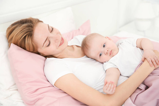 glückliche junge Frau mit süßem Baby zu Hause im Bett liegend - Foto, Bild