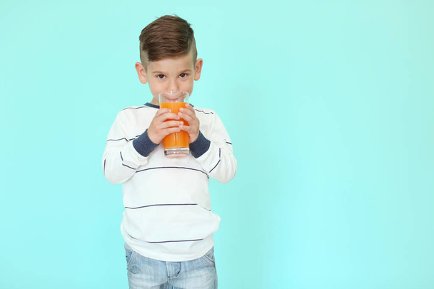 Cute little boy drinking juice on color background - Photo, Image