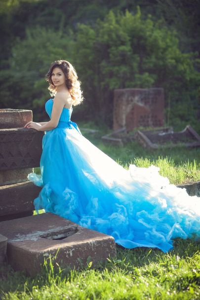 Young beautiful girl in a lush blue dress - Фото, зображення