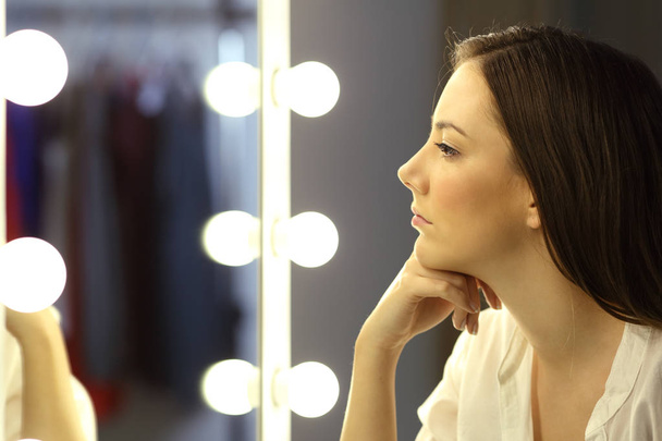 Serious woman looking at make up mirror - Foto, immagini