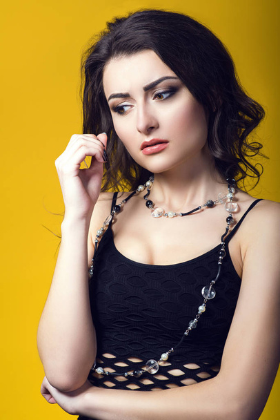 Retrato de una joven hermosa mujer de cabello oscuro preocupada vistiendo top de red negro y cuentas de vidrio mirando preocupado y molesto
 - Foto, imagen