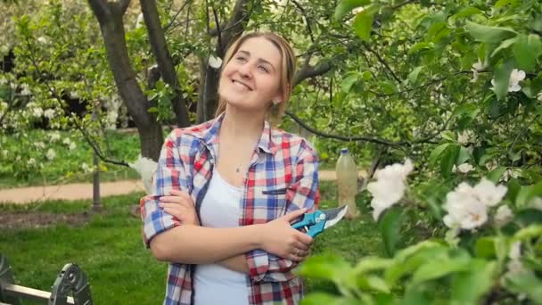 Lassú mozgás video boldog mosolygó nő pózol: orchard és látszó-on fényképezőgép - Felvétel, videó