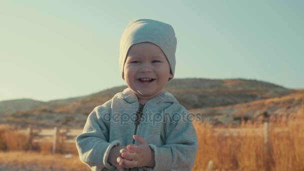 Rozkošný šťastný veselý Evropské chlapce usmívající se venku, hory v pozadí, pomalý pohyb - Záběry, video