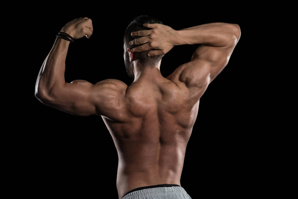 Muscular Model Flexing Muscles On Black Background - Фото, изображение